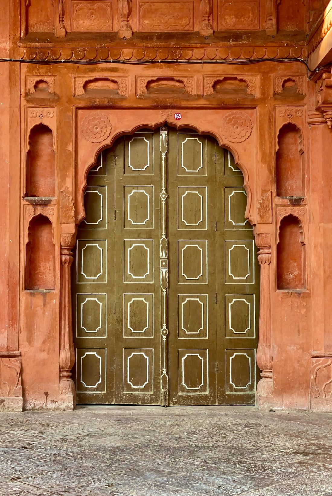 A carved red sandstone doorway with painted wooden doors in old Bikaner.